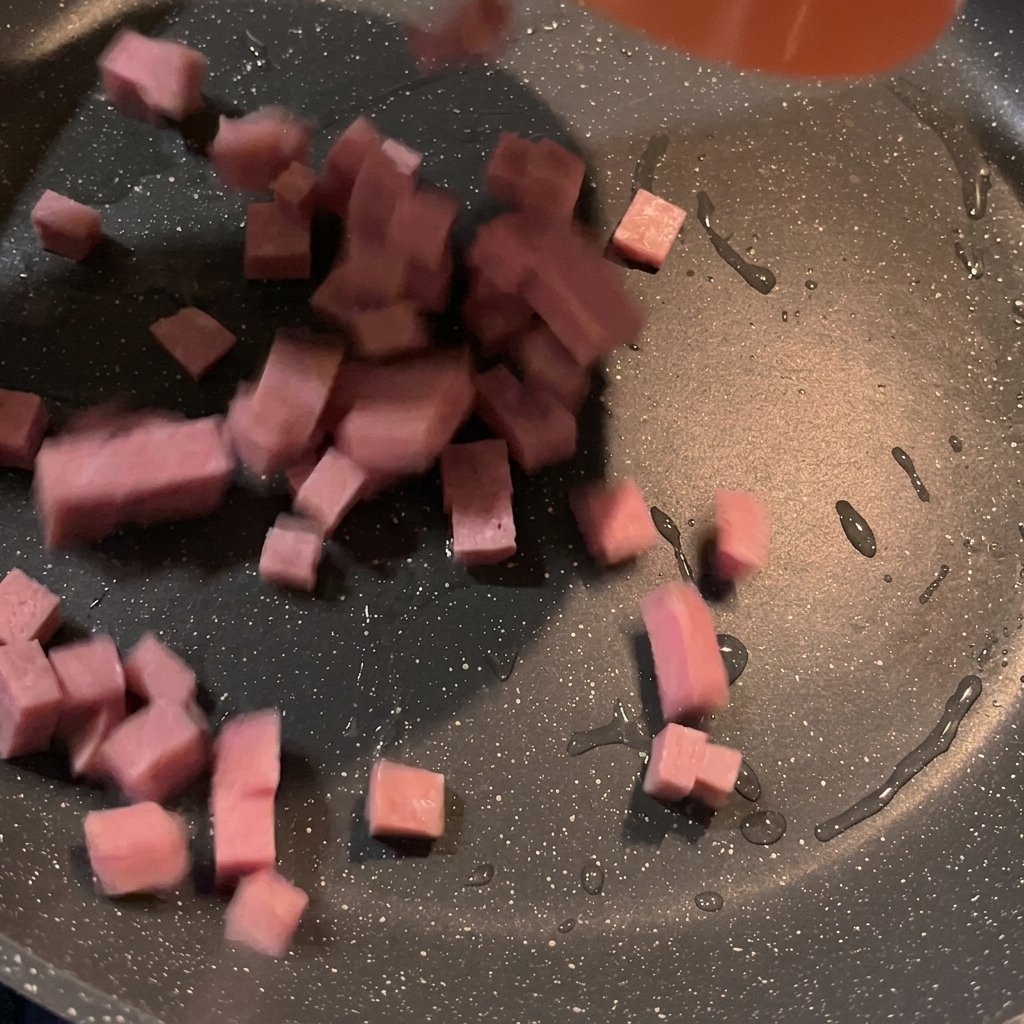 Cubetti di spam che sfrigolano e dorano in una padella calda.