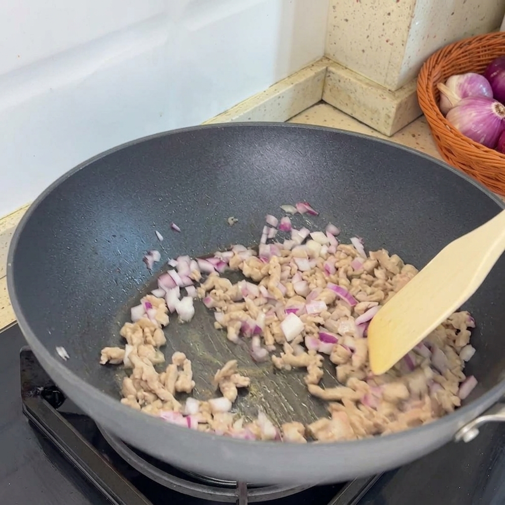 Scalogni tritati aggiunti alla padella e combinati con il maiale macinato cotto.