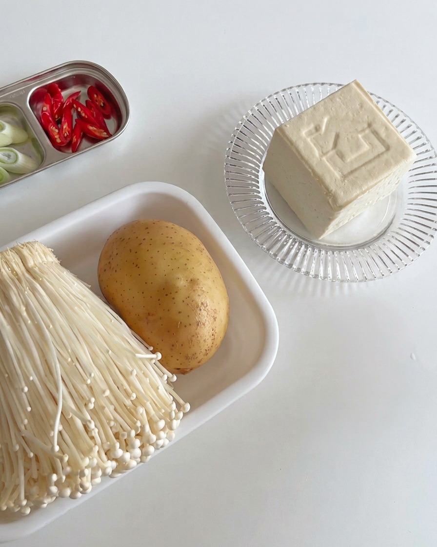 Spessi blocchi di tofu bianco sodo disposti su un tagliere di legno, pronti per essere cucinati.