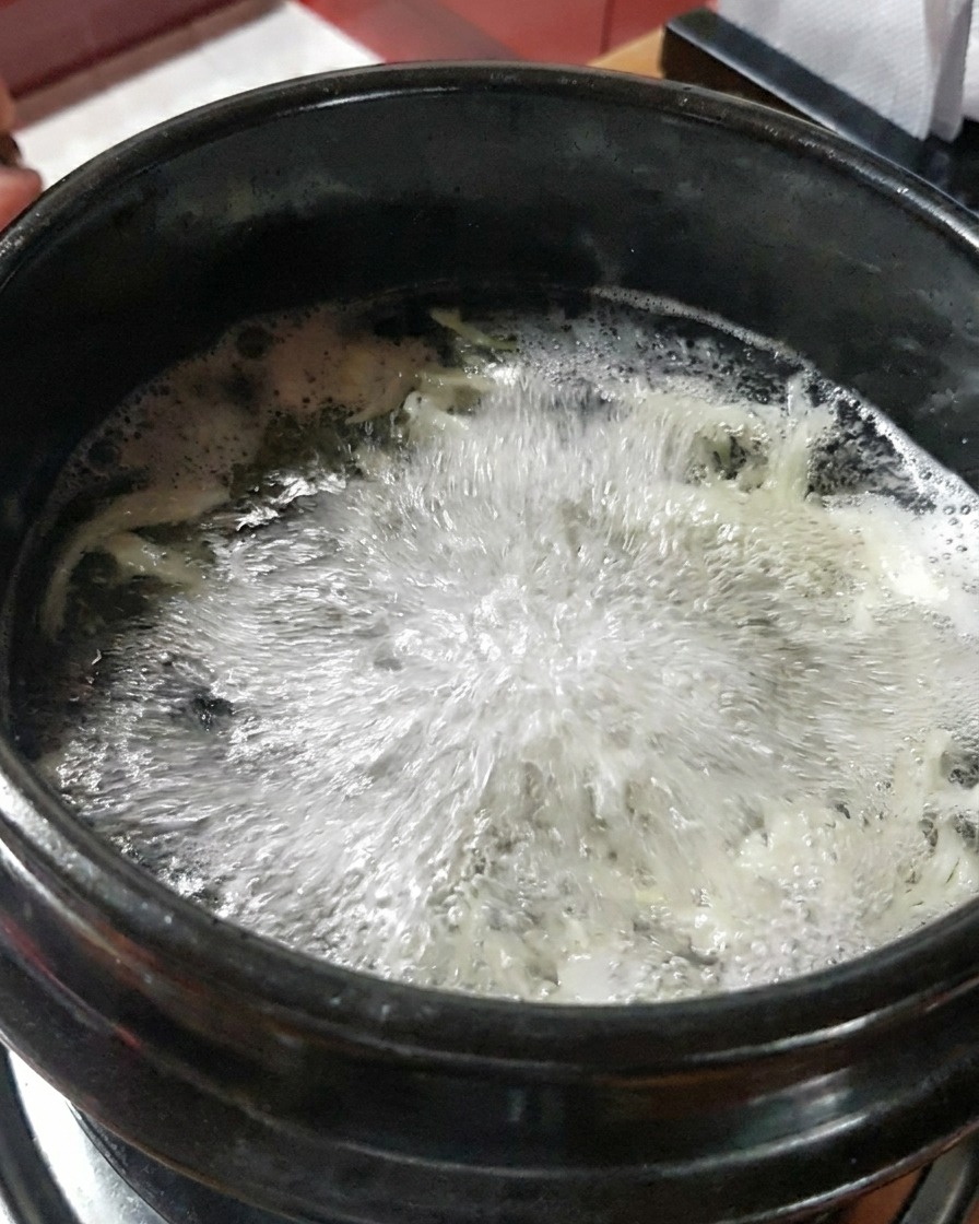 Gamberi crudi traslucidi versati nel brodo di pesce in ebollizione.