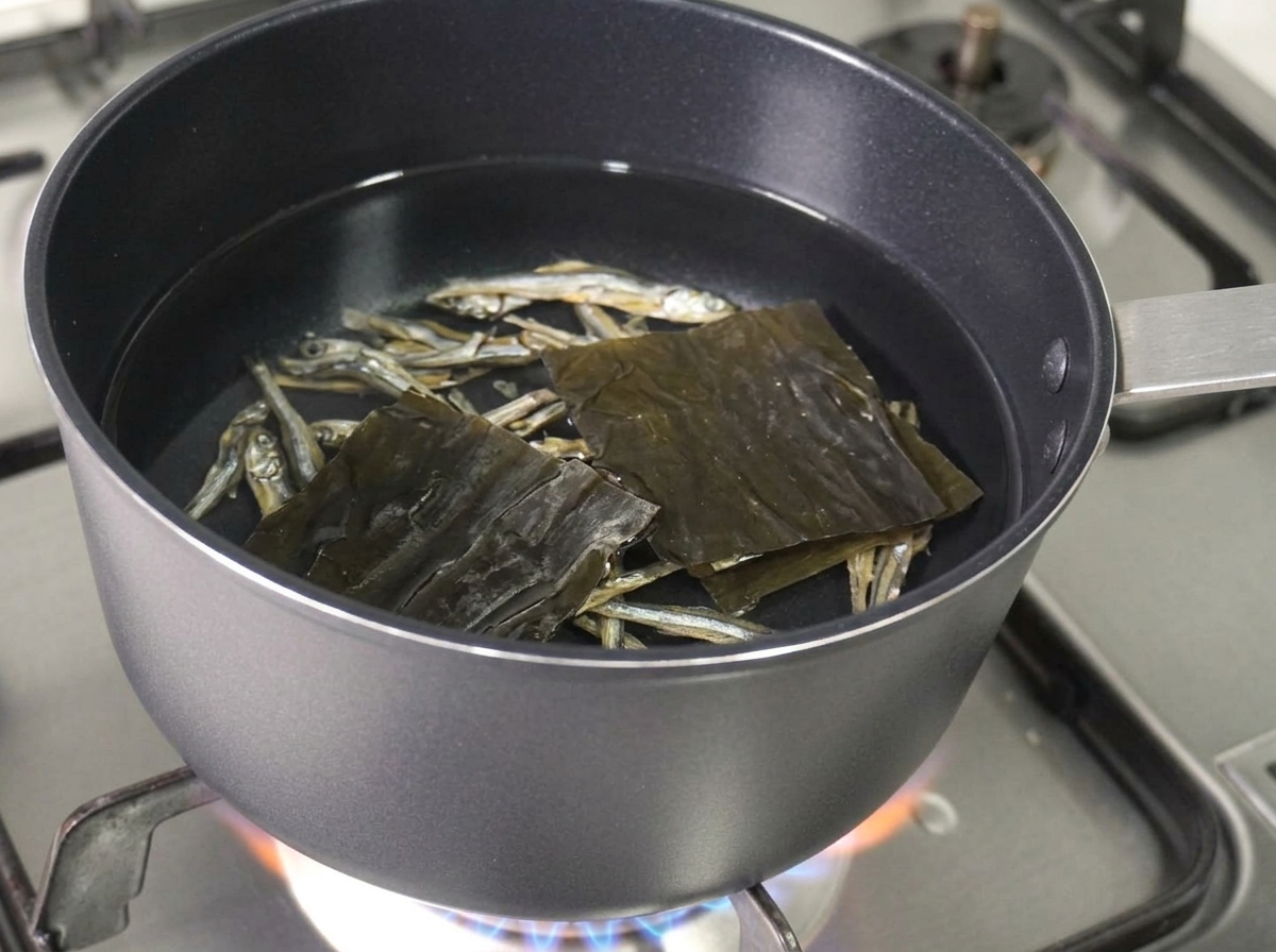 Acciughe essiccate e un pezzo quadrato di alga kelp essiccata che galleggiano nella pentola dacqua.