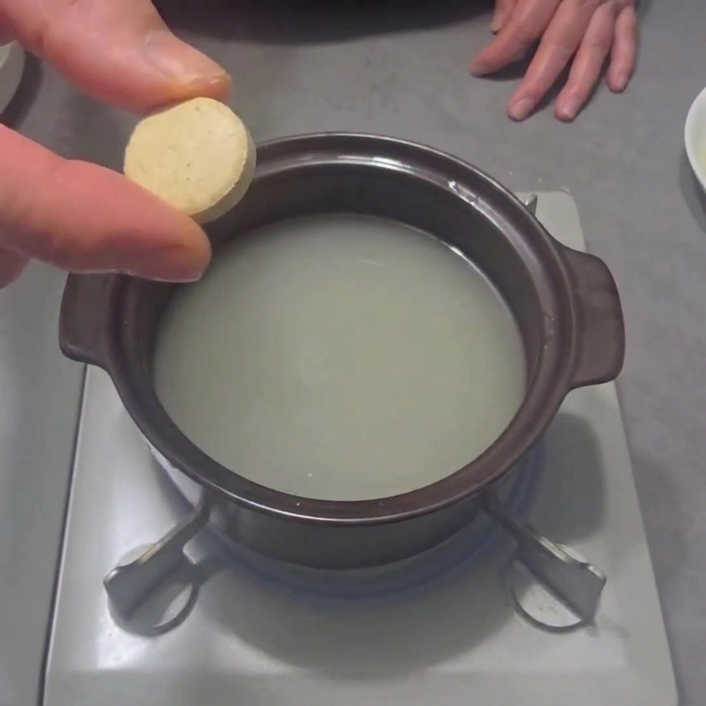 Un cubetto di brodo ai frutti di mare versato in una pentola dacqua sul fornello.