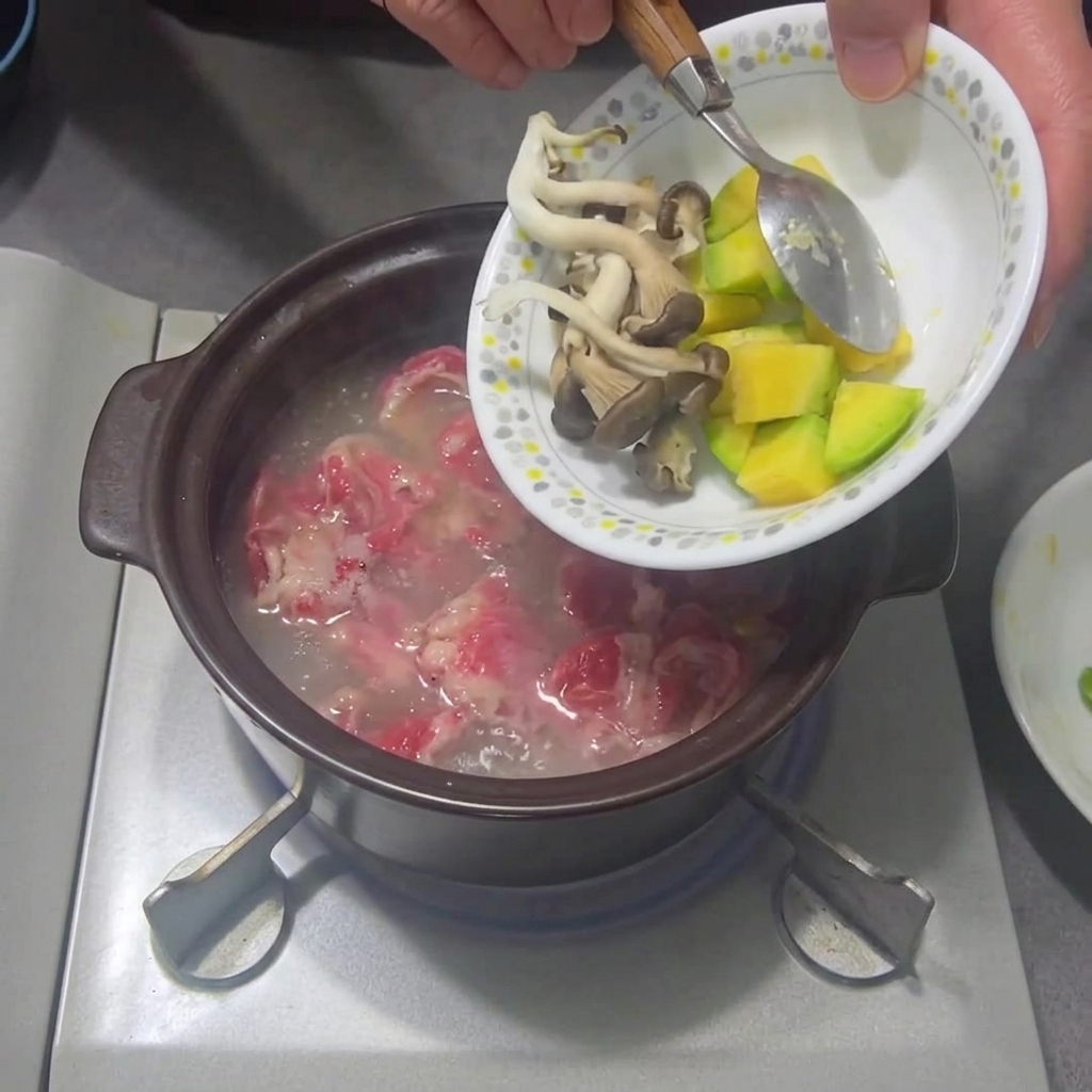 Fette di funghi e zucchine aggiunte allo stufato che sobbolle.