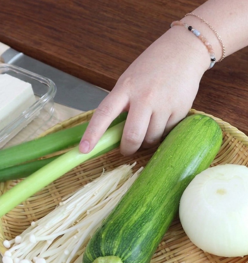 Rondelle di cipollotto tritate finemente disposte su un tagliere di legno.