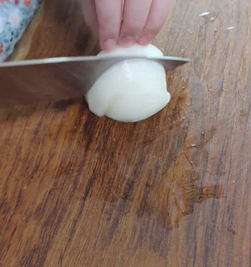 Piccoli pezzi di cipolla a cubetti su un tagliere di legno, pronti per la pentola.