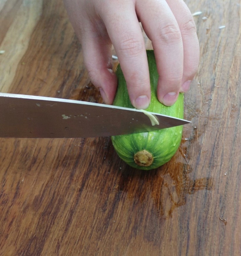 Pezzi di zucchina affettati a triangolo su un tagliere di legno.