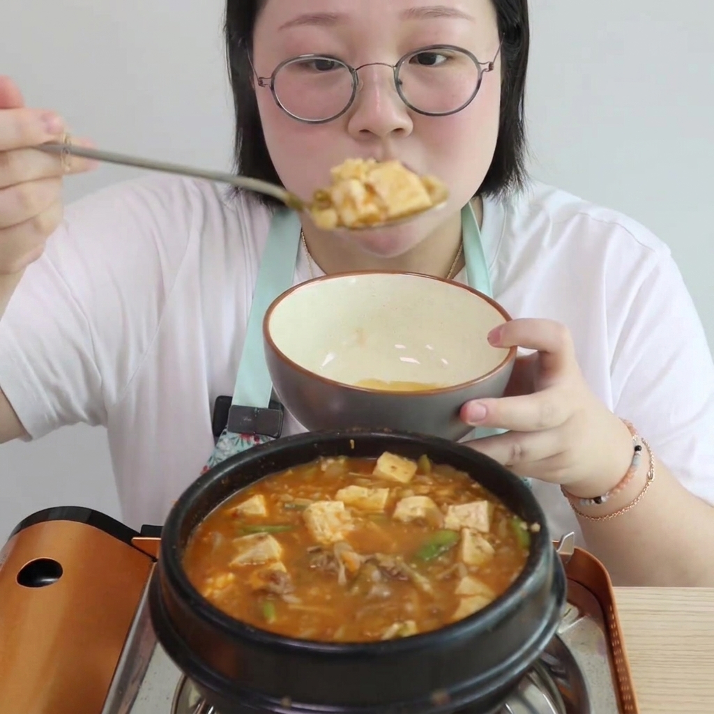 Tofu a cubetti e sezioni di funghi enoki aggiunti allo stufato bollente.