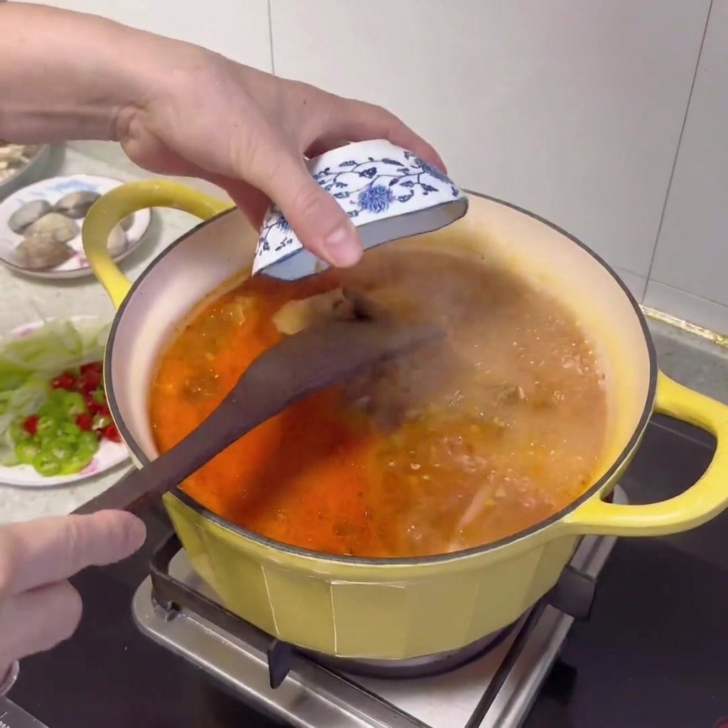 Un cucchiaio di legno che aggiunge una dose di pasta di soia coreana nel brodo bollente.