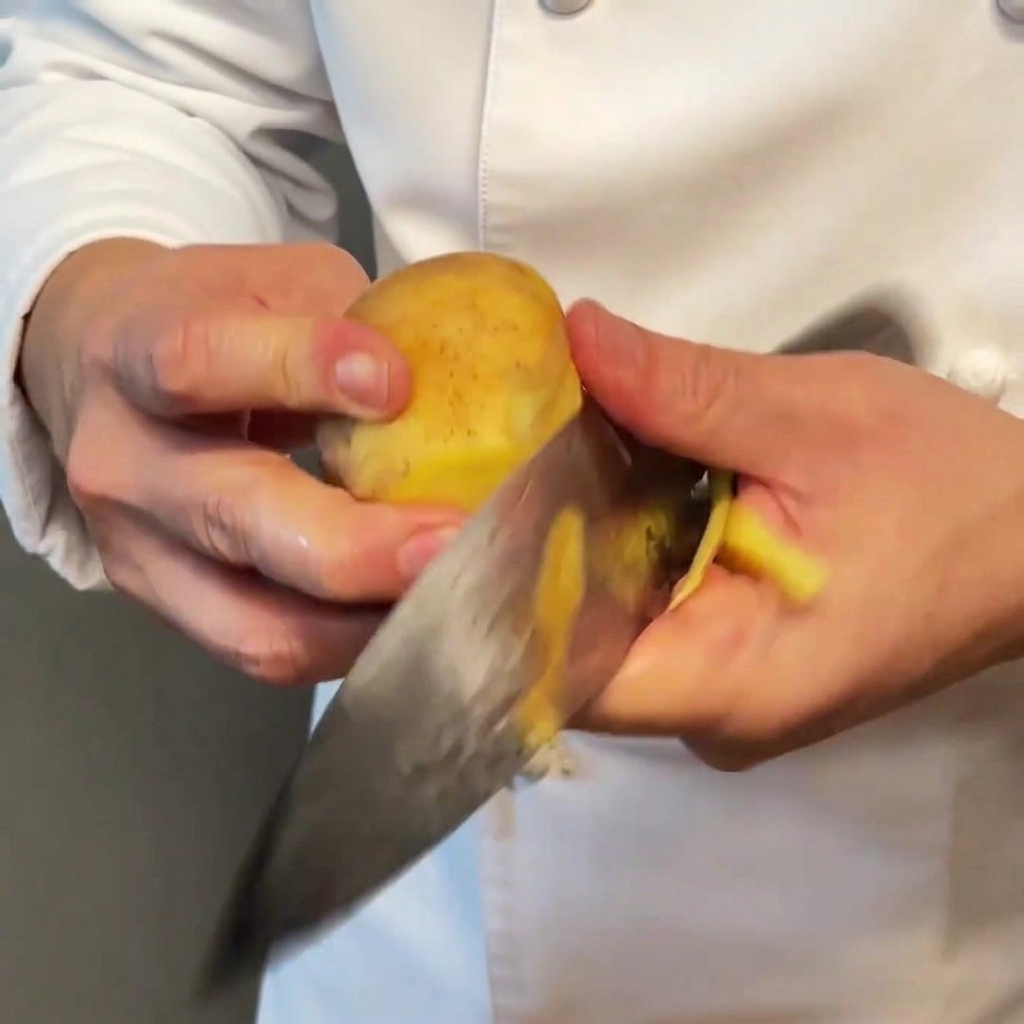 Cubetti di patate tagliati uniformemente pronti per la cottura su una superficie in legno.