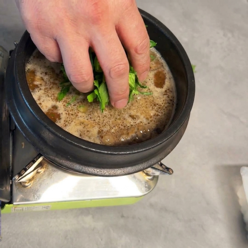 Foglie di baby bok choy fresco immerse nel Doenjang-jjigae in sobbollizione.
