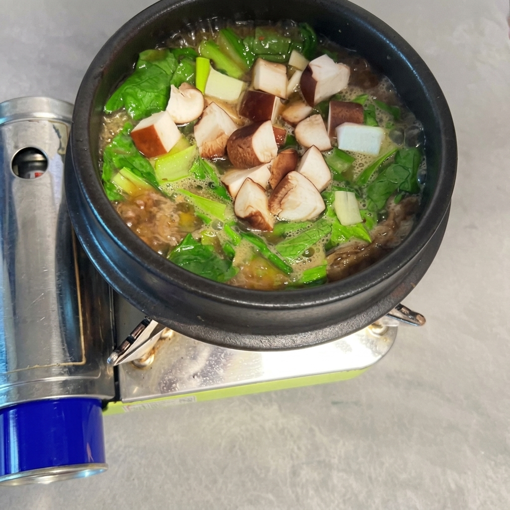 Funghi shiitake a dadini sparsi nel Doenjang-jjigae bollente.