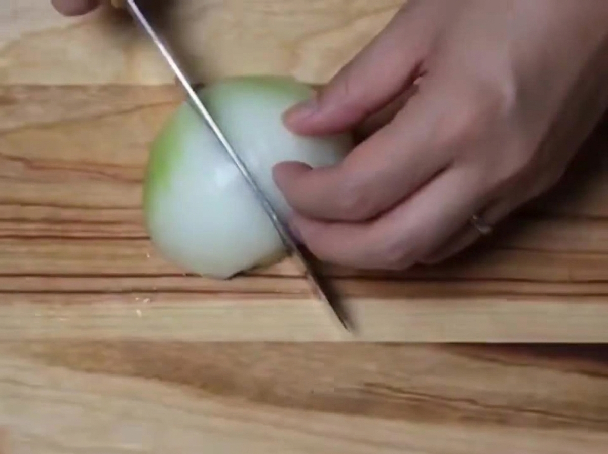 Una cipolla bianca tritata in piccoli pezzi su un tagliere di legno.