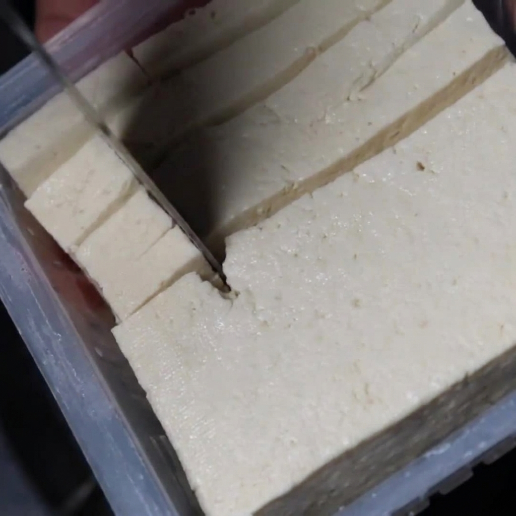 Cubetti di tofu bianco aggiunti allo stufato in ebollizione.