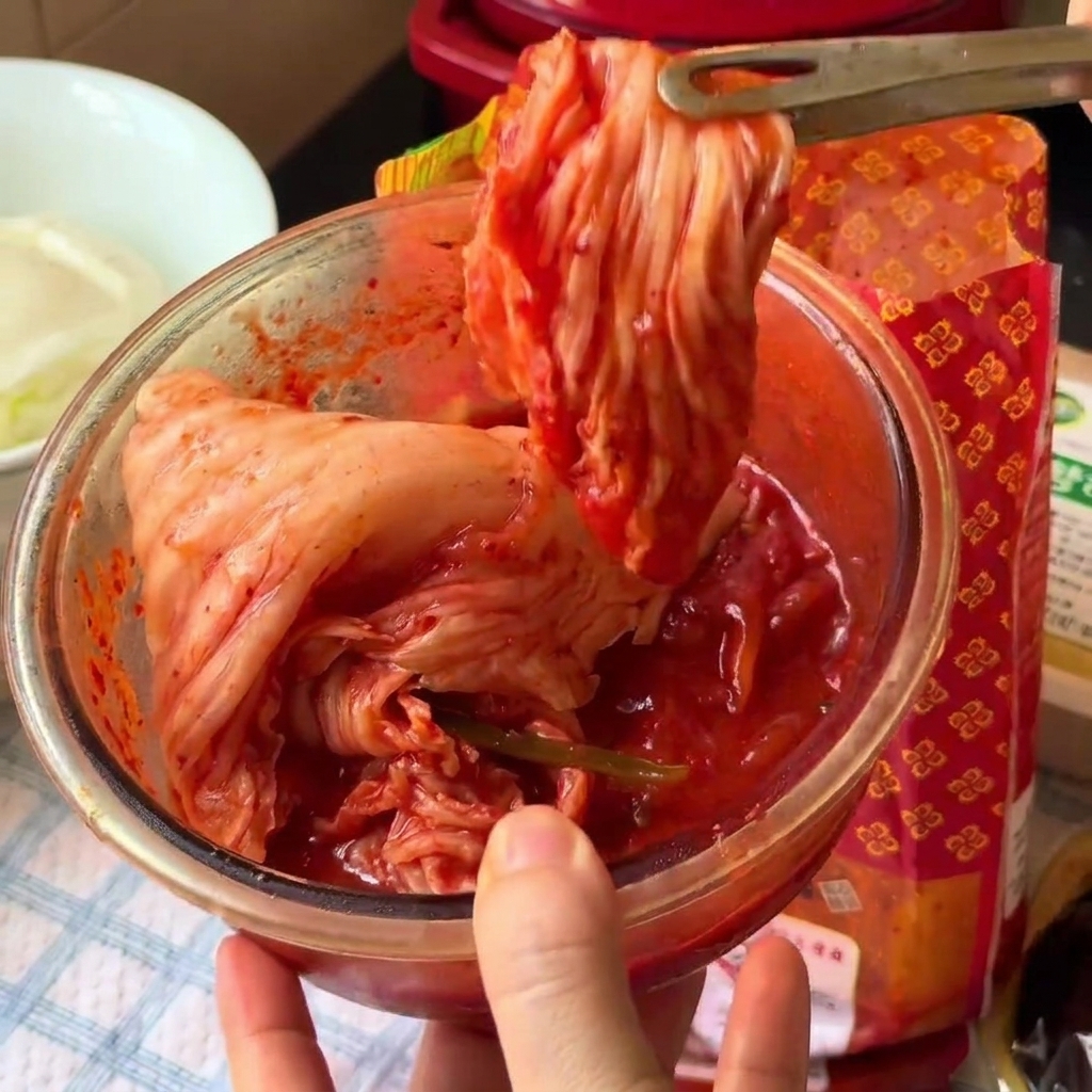 Kimchi tagliato a pezzetti allinterno di una ciotola di vetro usando forbici da cucina.