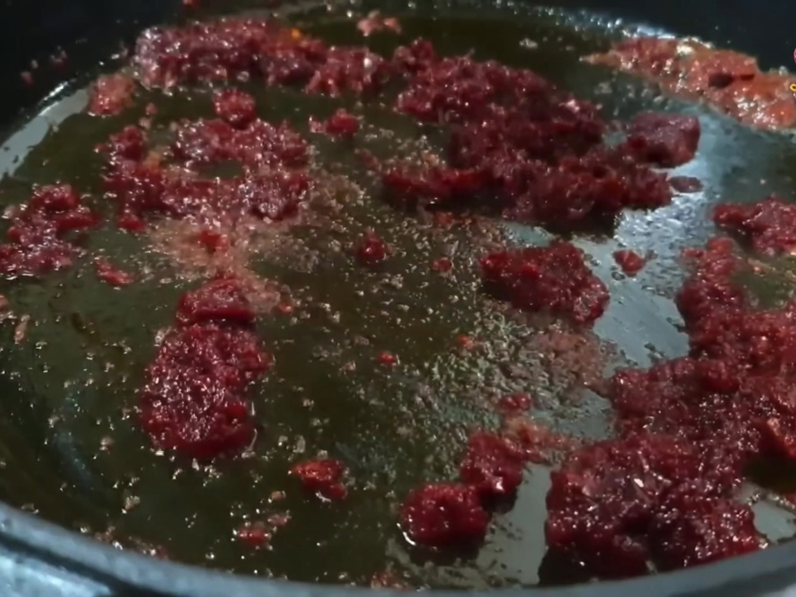 Pezzi di maiale mescolati nel soffritto rosso piccante.