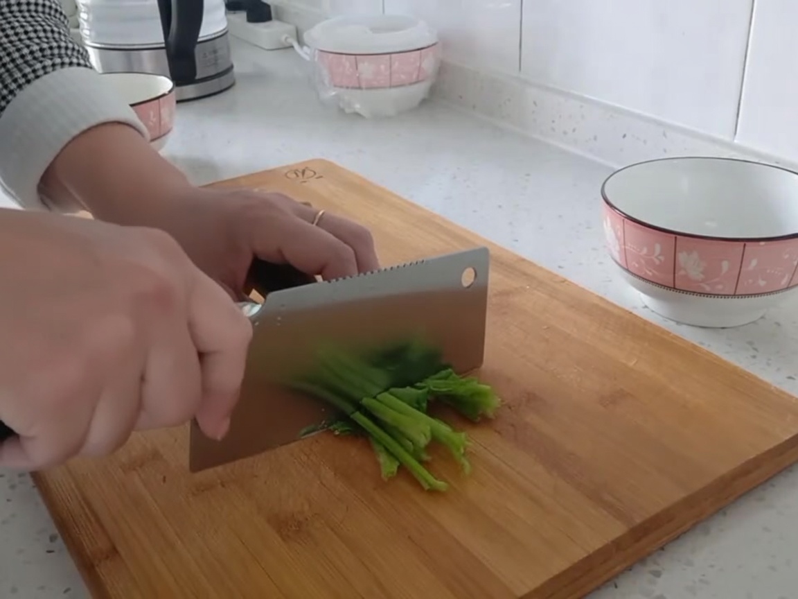 Foglie di spinaci freschi tagliate in pezzi a misura di boccone su un tagliere.