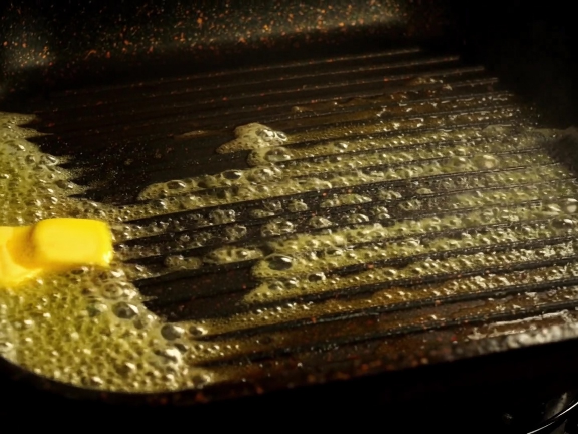 Metà di un panino da hamburger tostate in una piastra con burro fuso.