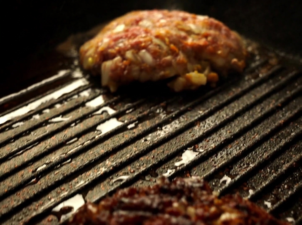Vista ravvicinata di una polpetta di Wagyu girata con una spatola in una piastra calda.