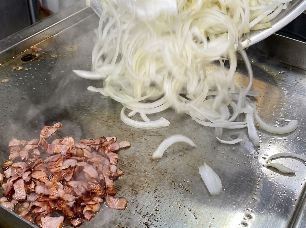 Un grande mucchio di cipolle bianche crude affettate finemente versate su una piastra piatta accanto a un mucchio di pezzi di bacon cotti.