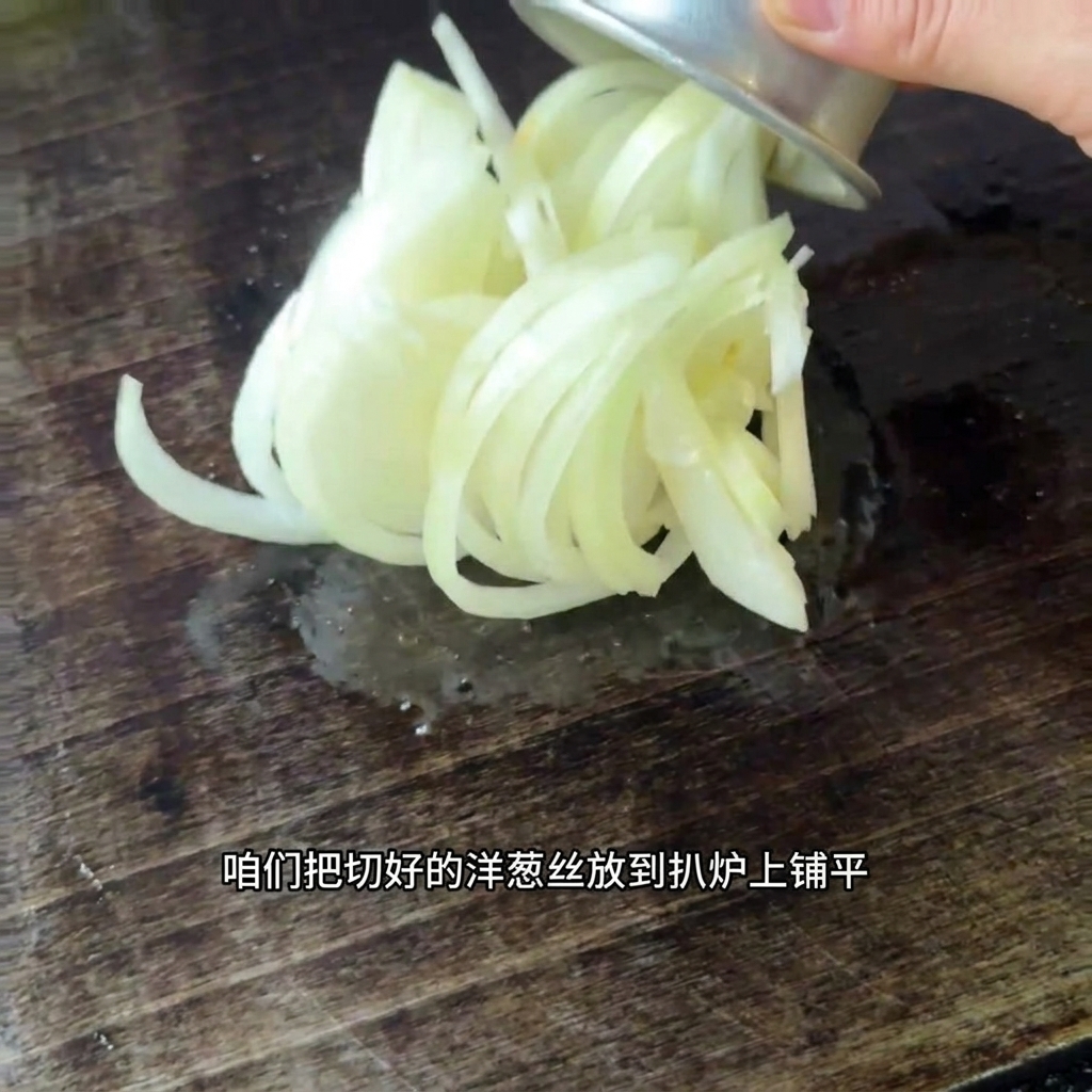 Cipolle appena affettate distribuite sulla superficie di una piastra calda.