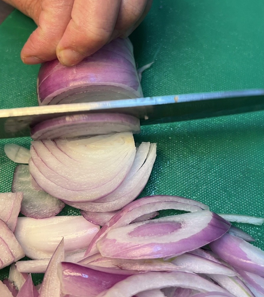 Cipolle affettate con cura su un tagliere verde.