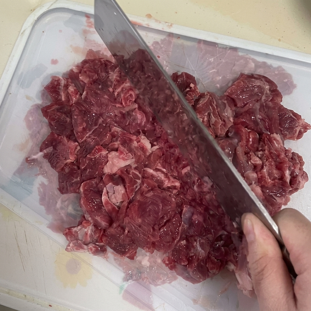Carne fresca tritata al coltello su un tagliere.