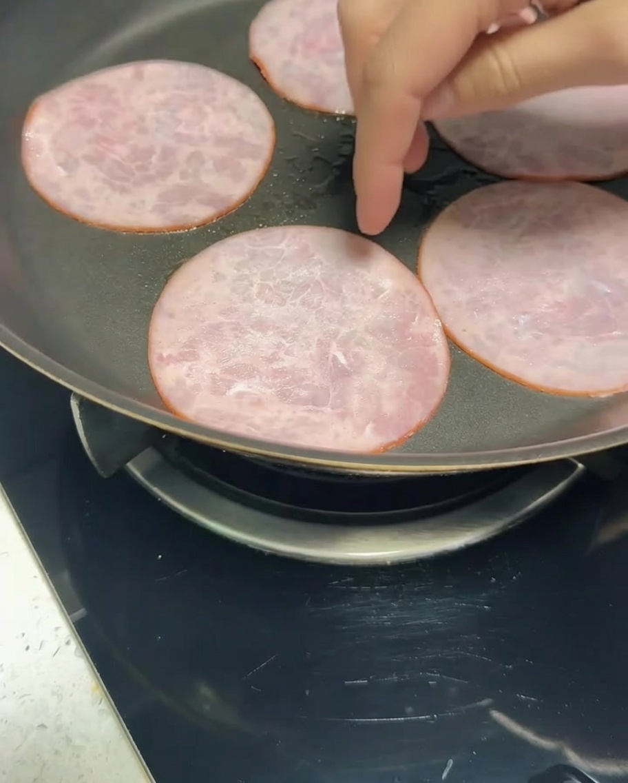 Strisce di pancetta magra in padella che diventano dorate.
