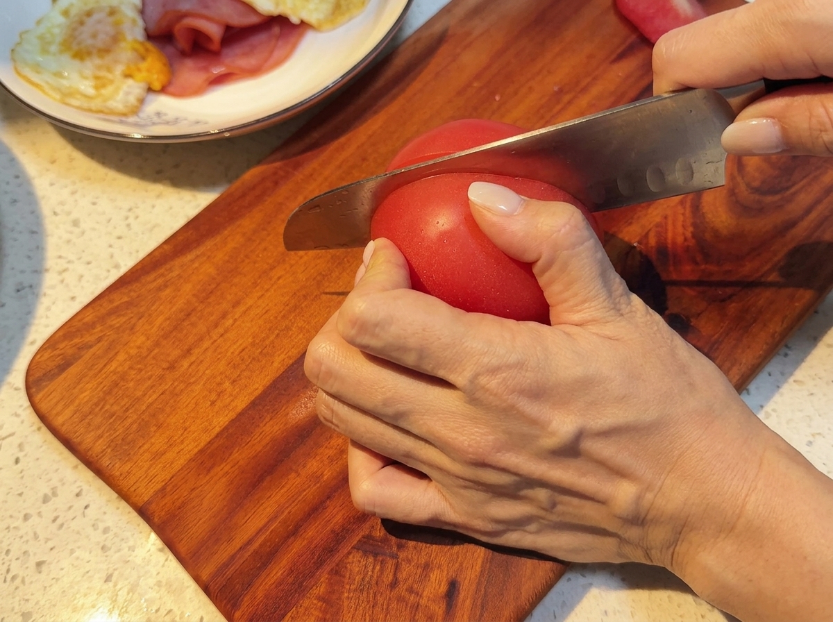 Pomodori freschi tagliati a fette uniformi su un tagliere.