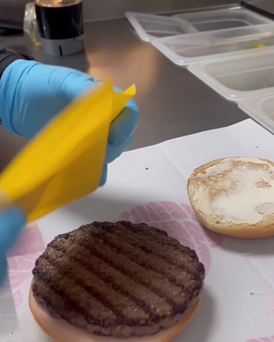 Dettaglio di una fetta di formaggio cheddar giallo su un tortino di manzo grigliato.