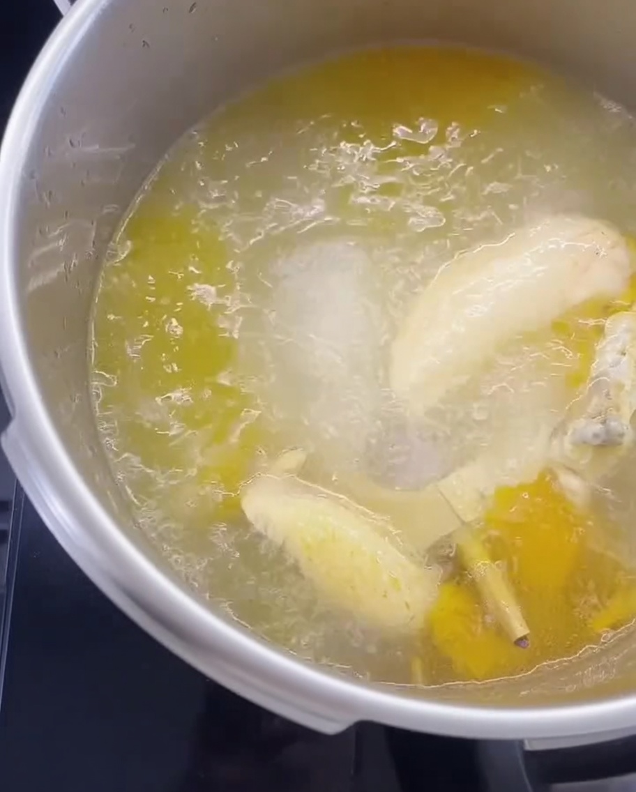 Noodles secchi immersi in una pentola di brodo di pollo bollente.