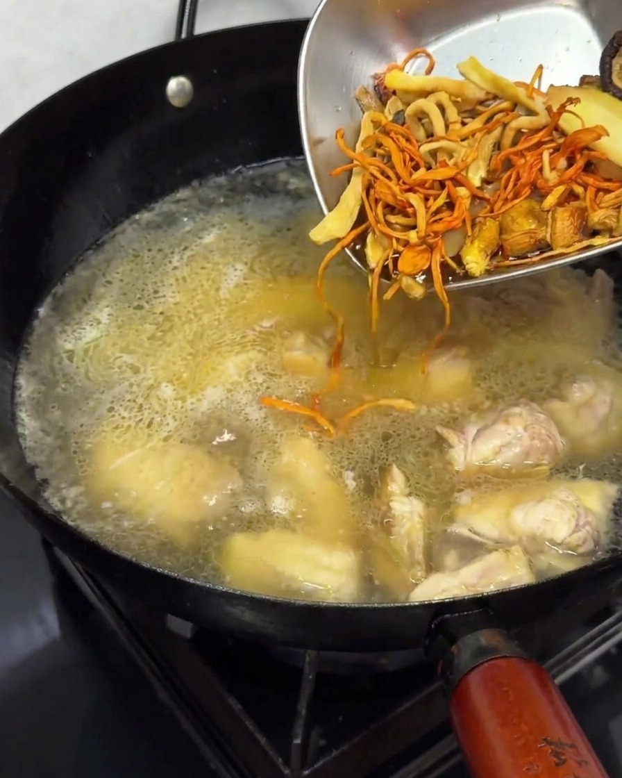 Aggiunta di funghi essiccati ammollati in un brodo di pollo in ebollizione.