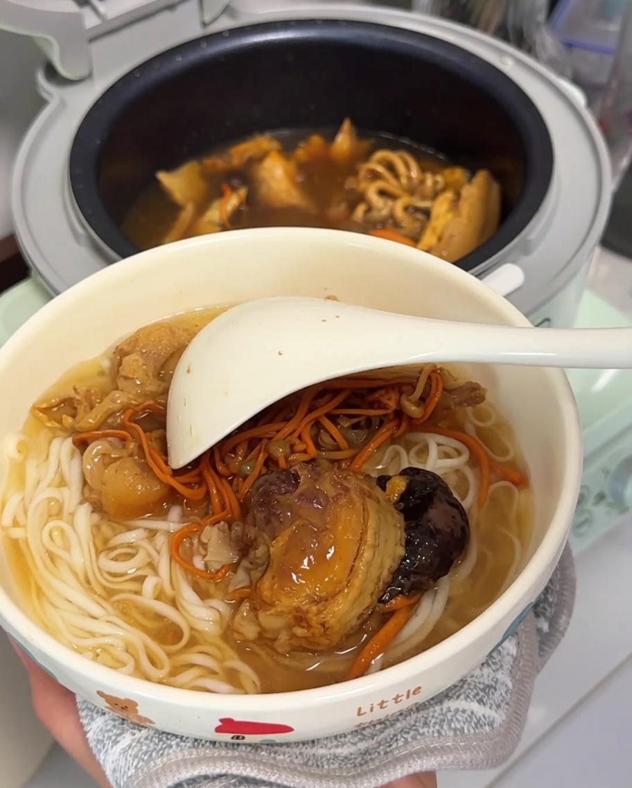 Una ciotola piena di noodles cotti con pollo e funghi, pronta per essere servita.