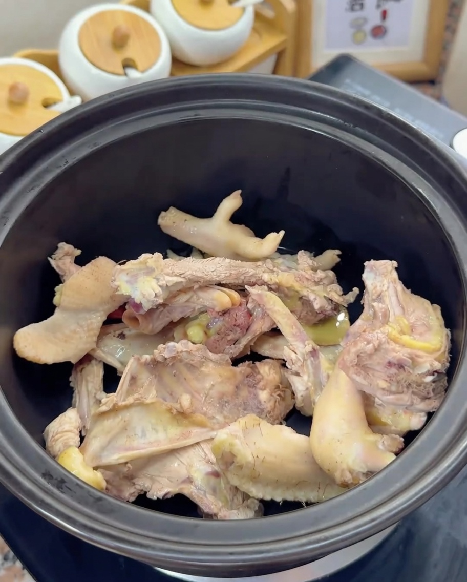 Ossa di pollo sbollentate che riposano sul fondo di un coccio nero.