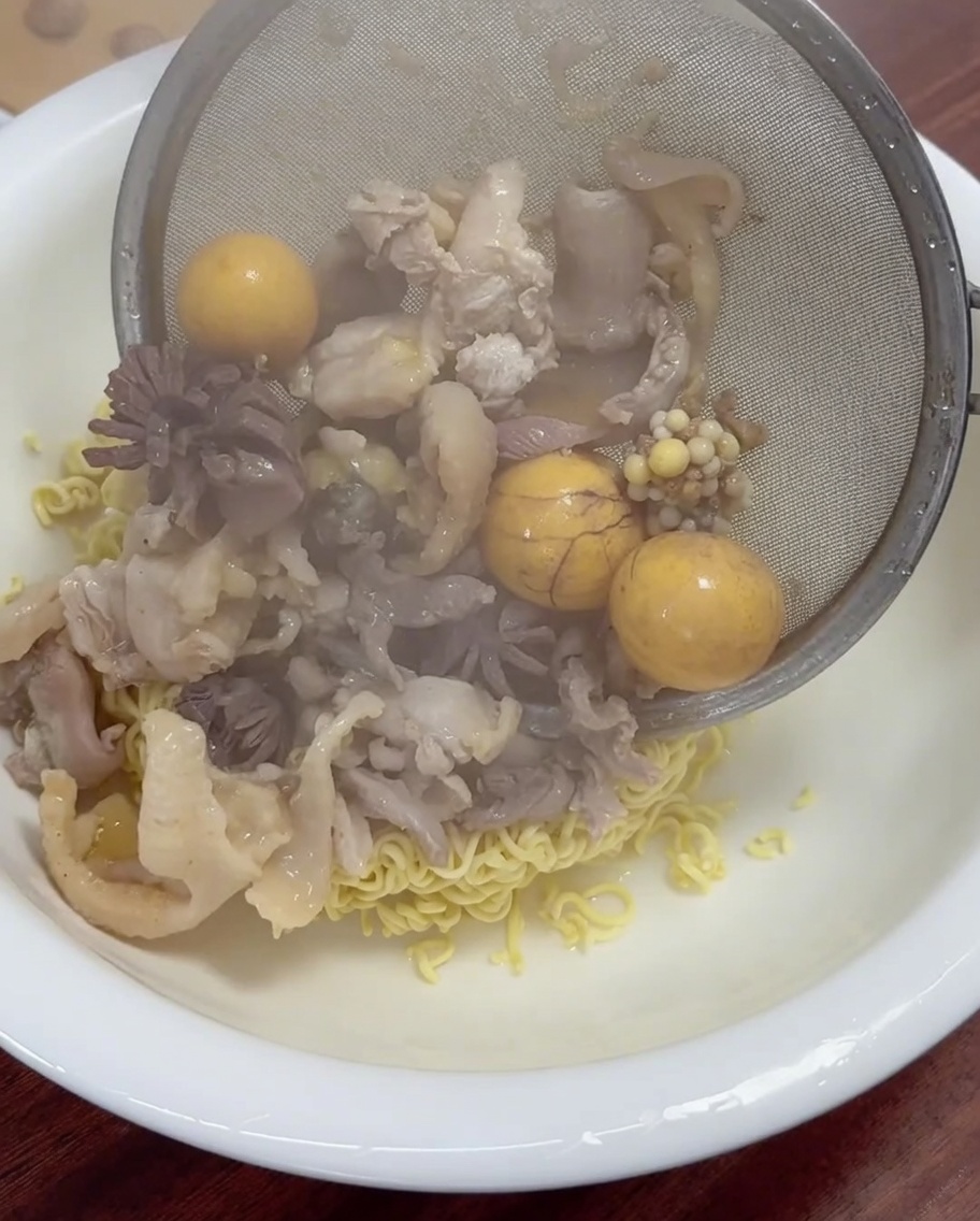 Carne di pollo appena cotta e tuorli gialli filtrati e posti in una ciotola di noodles.
