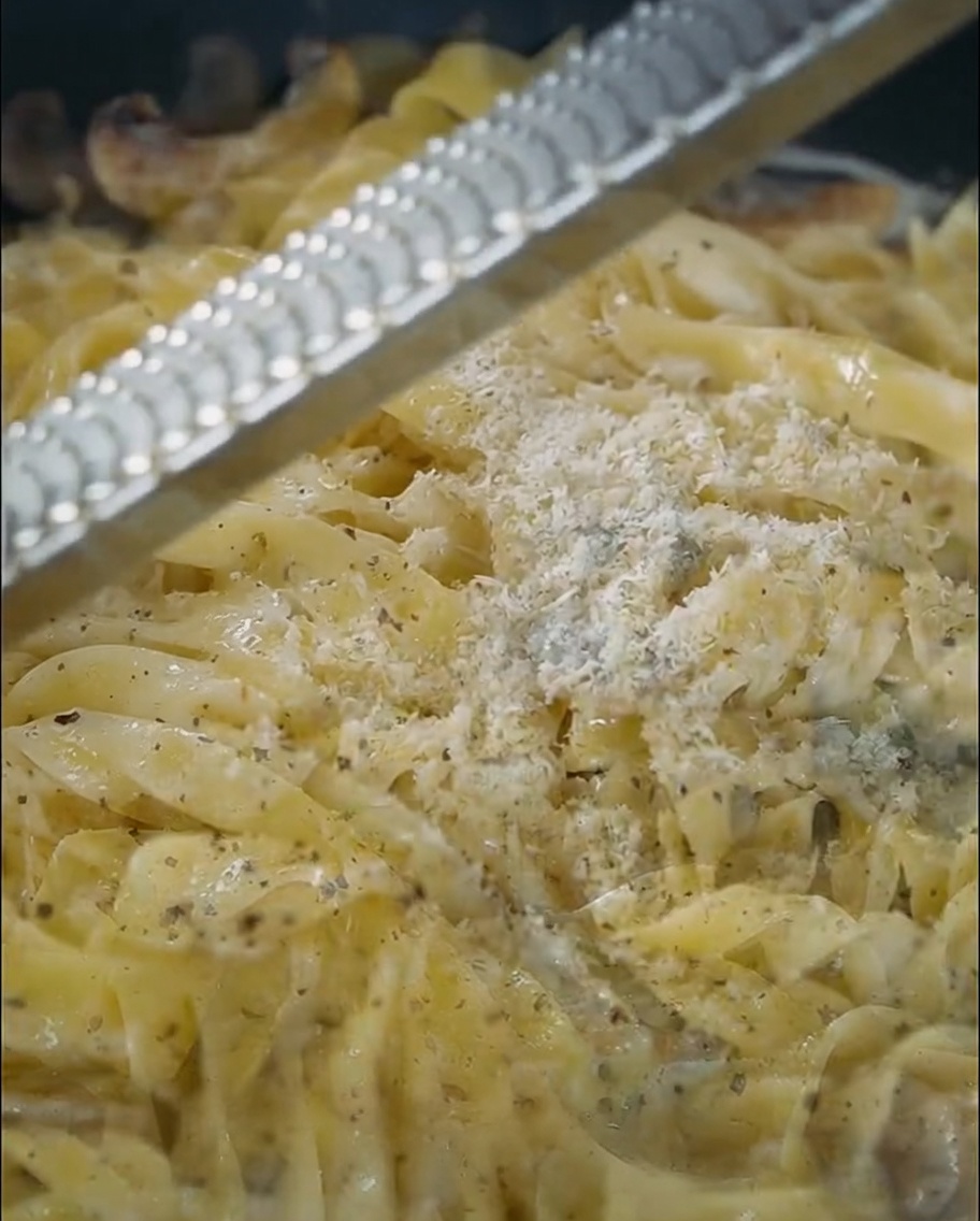 Formaggio grattugiato fresco sulla pasta in padella.