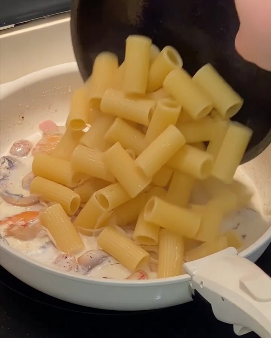 Rigatoni cotti aggiunti nella padella con la salsa cremosa.