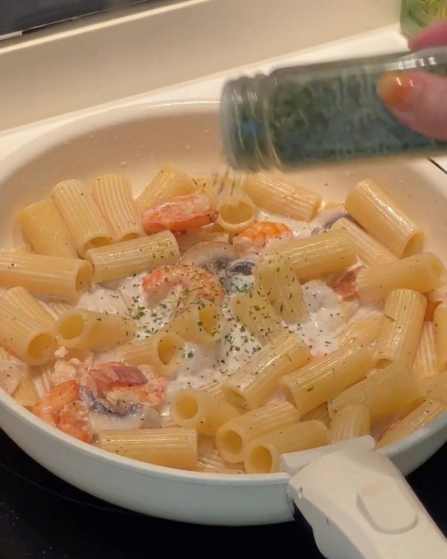 Prezzemolo fresco tritato cosparso sui rigatoni pronti in padella.