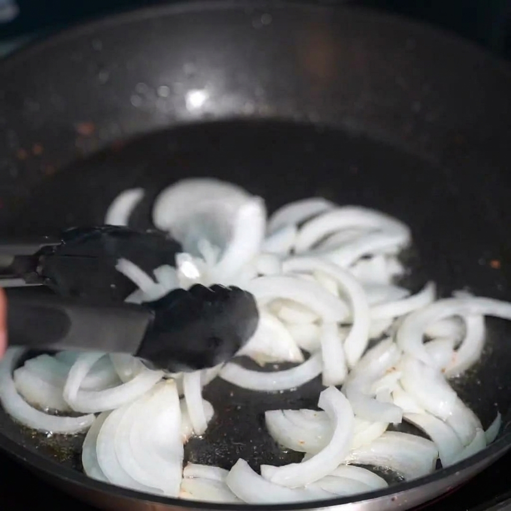 Cipolle affettate che soffriggono nel grasso di pancetta dorato.