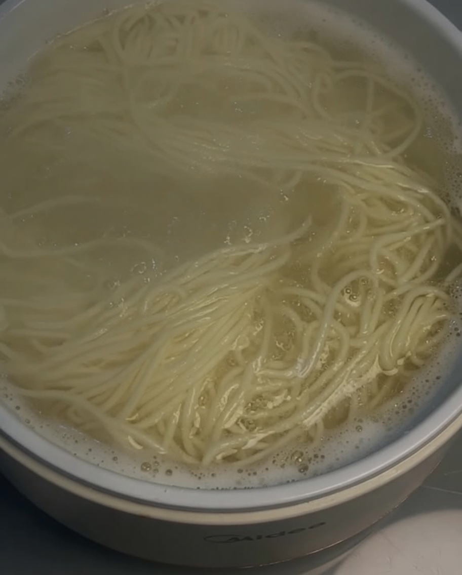 Uno scolapasta solleva i noodles cotti da una pentola.
