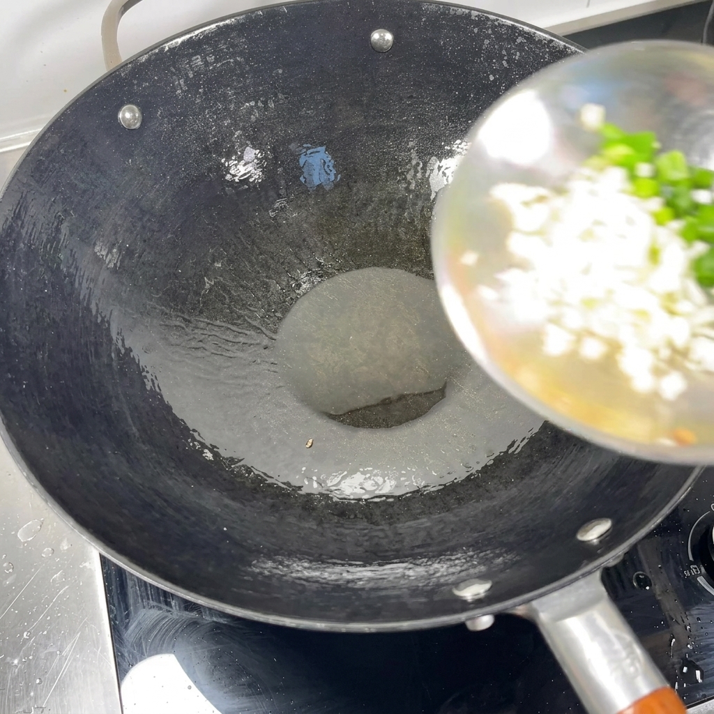 Cipollotti tritati e aglio tritato aggiunti da un mestolo in un wok caldo con olio.