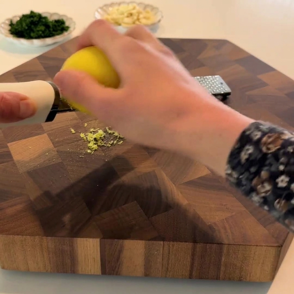 Un limone grattugiato con una zester, mostrando la scorza gialla raccolta.