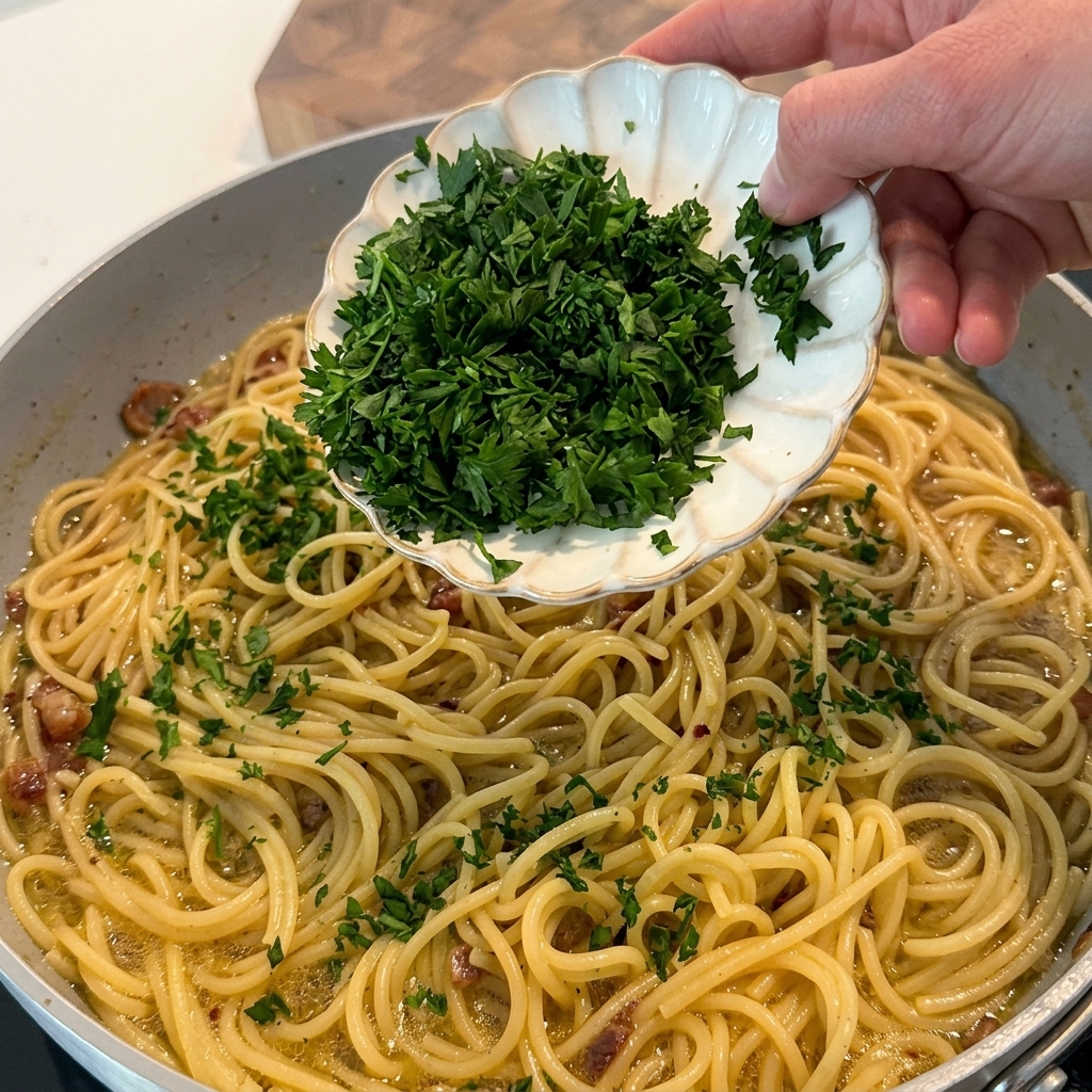 Prezzemolo fresco tritato aggiunto sulla pasta nel piatto.