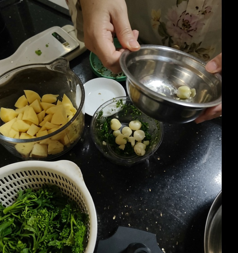 Spicchi daglio sbucciati allinterno della ciotola trasparente di un tritatutto manuale.