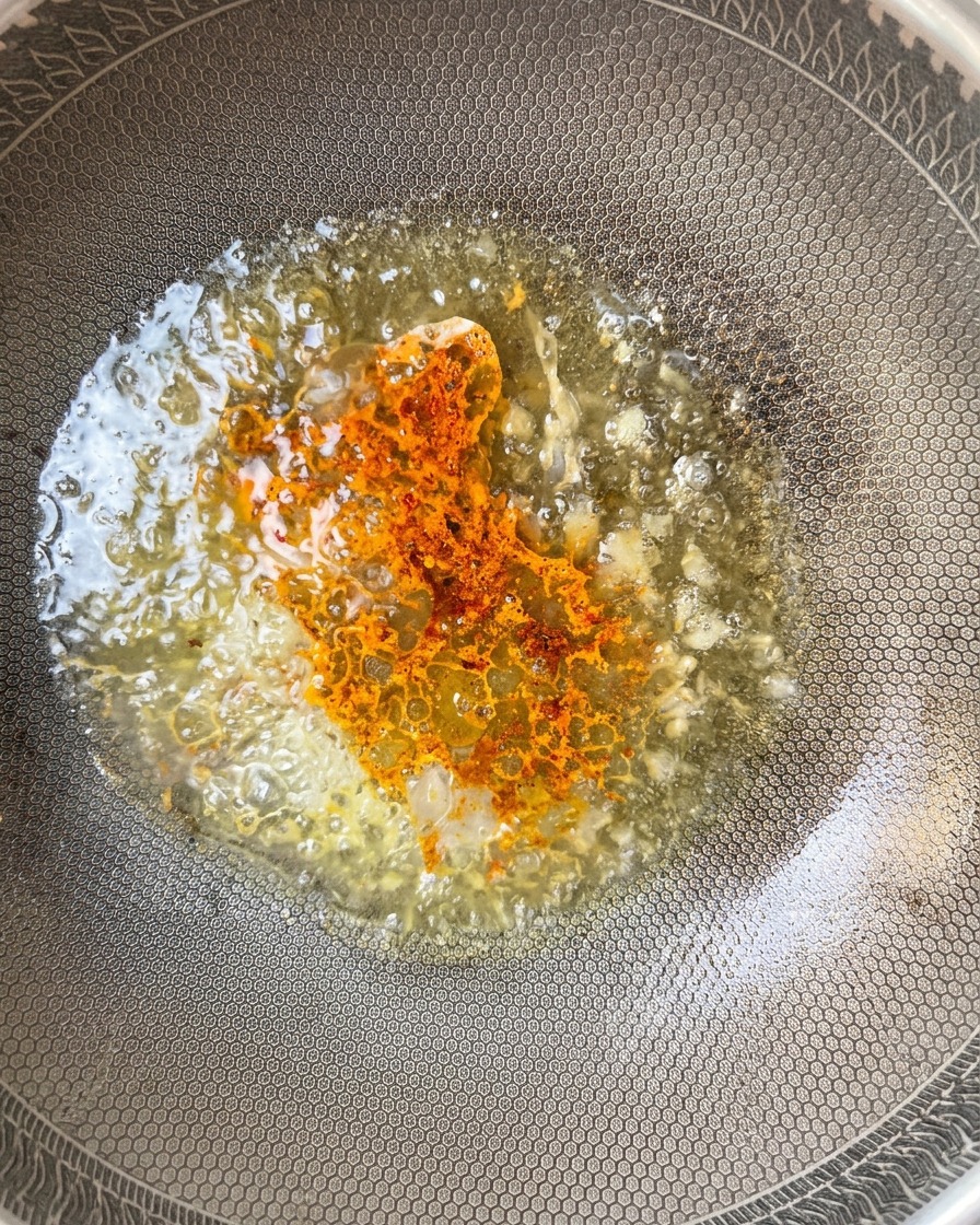 Polvere di peperoncino aggiunta alla salsa in padella.