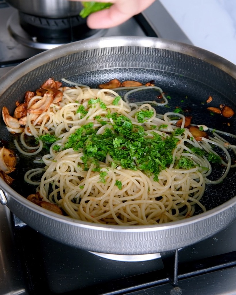 Prezzemolo fresco tritato aggiunto sopra agli spaghetti aglio e olio.