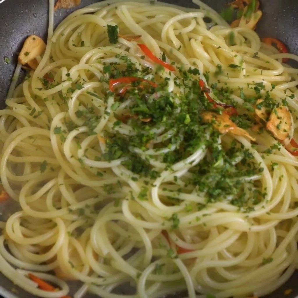 Prezzemolo fresco tritato cosparso sugli spaghetti nella padella.