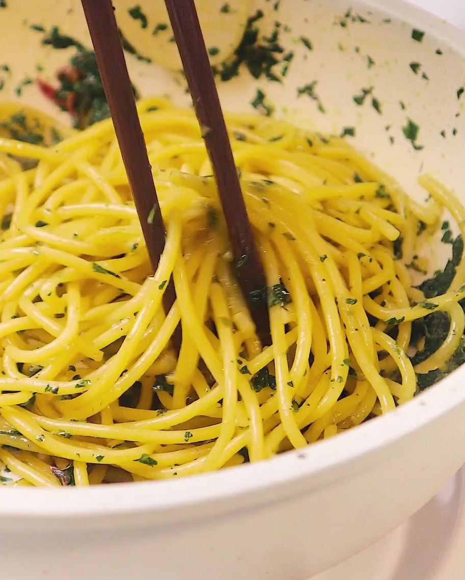 Fettine sottili di aglio che friggono in olio doliva dorato in una padella bianca.