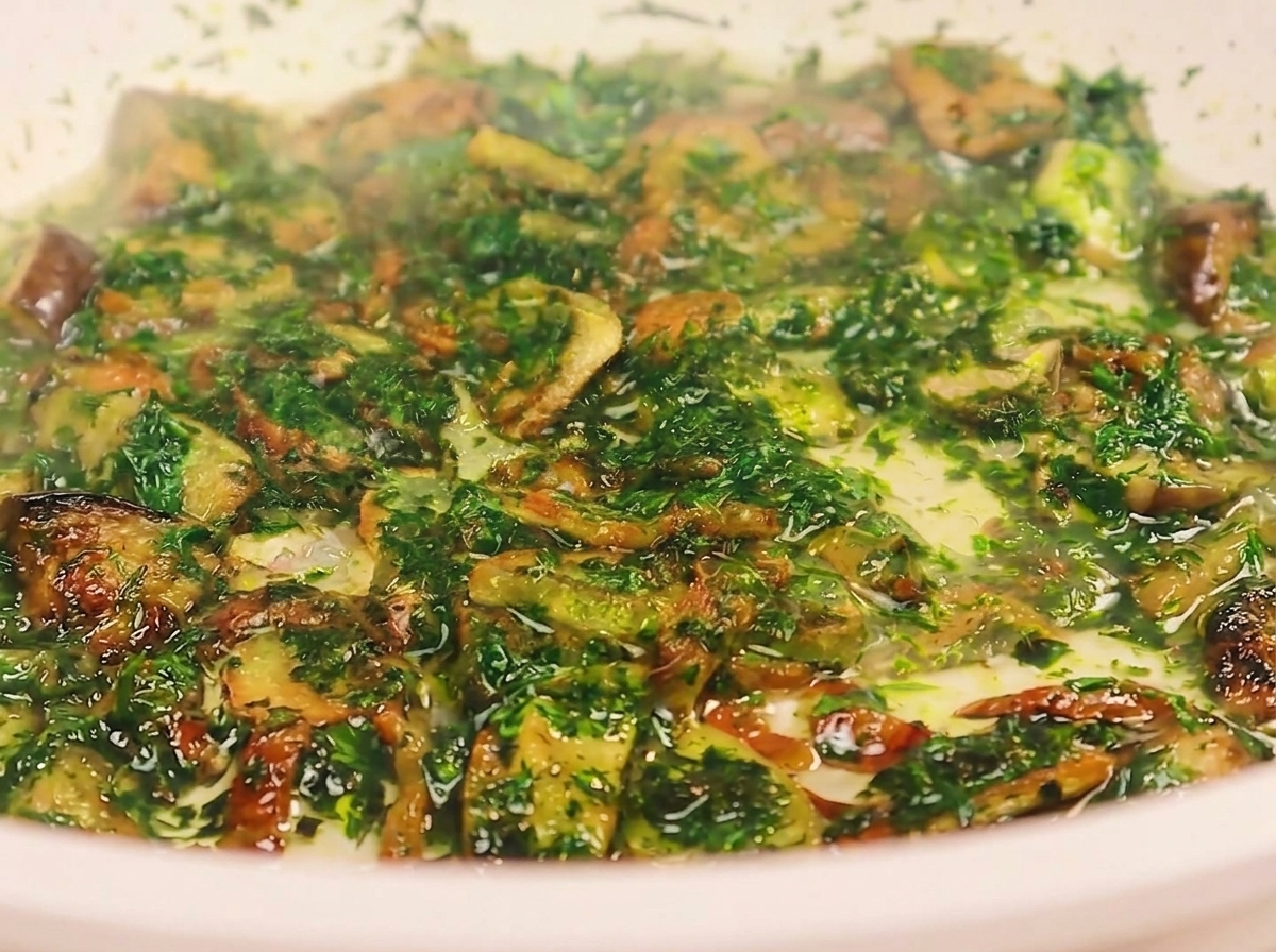 Un mestolo versa lacqua torbida della pasta in una padella contenente pancetta fritta, aglio e prezzemolo tritato.