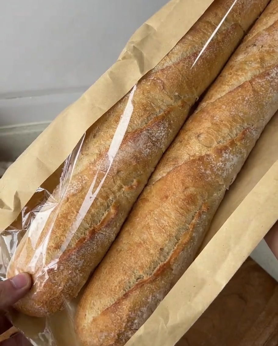 Fette diagonali di baguette disposte su un tagliere, pronte per essere condite.