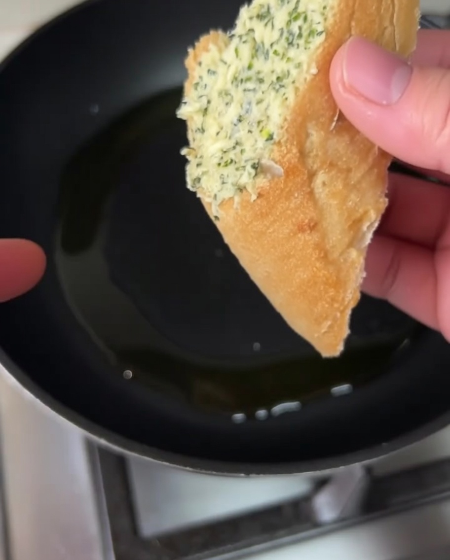 Fette di pane condite che sfrigolano in padella con lolio.